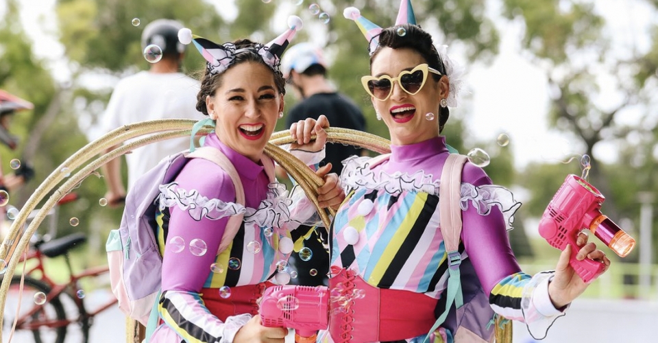 Two people in colourful costumes smiling on the camera.
