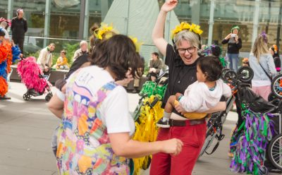 A group of women dancing with colourful prams and their children for Pram People