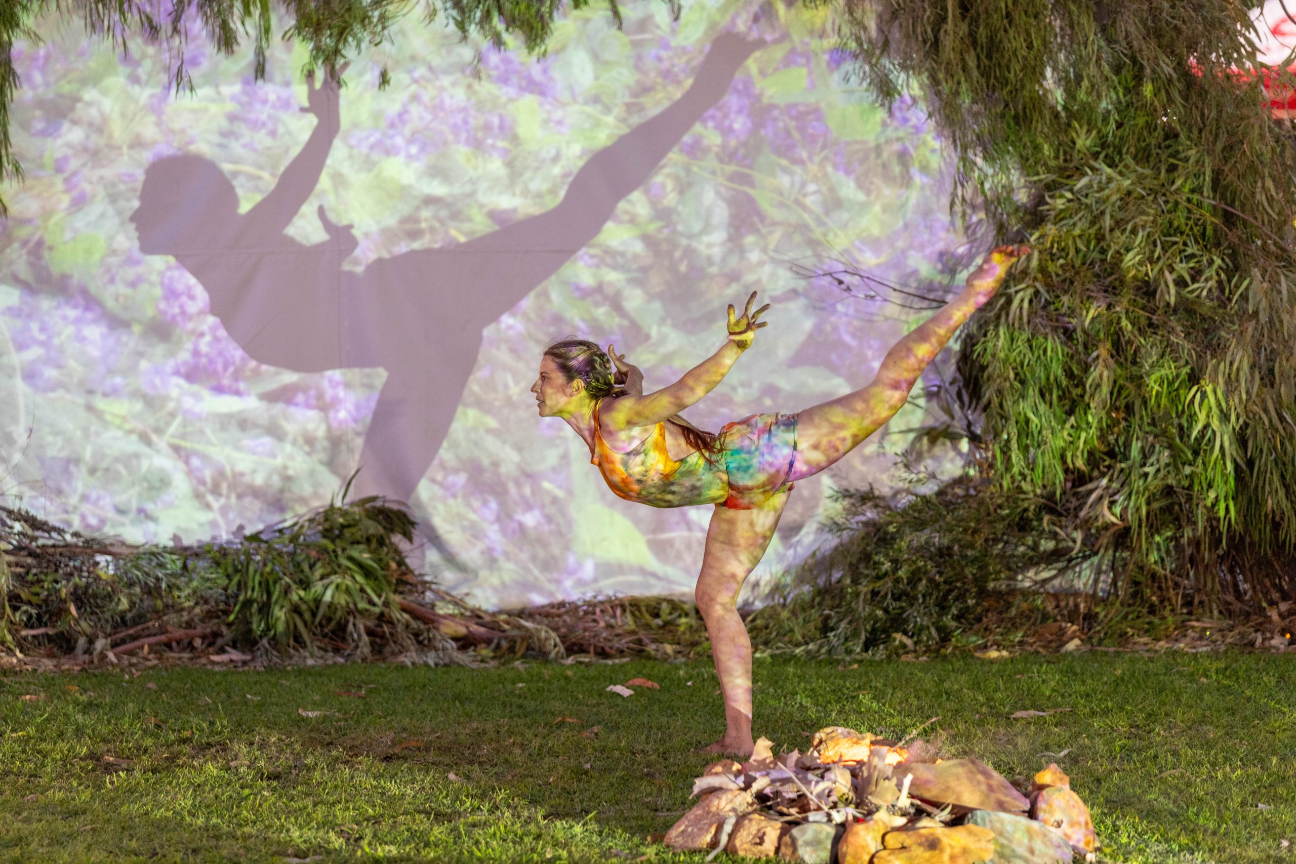 a performer dancing on grass with colourful projections overlaid