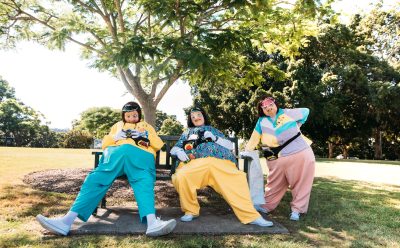The tourists dressed in colourful tracksuits and holding maps and cameras rest on a park bench